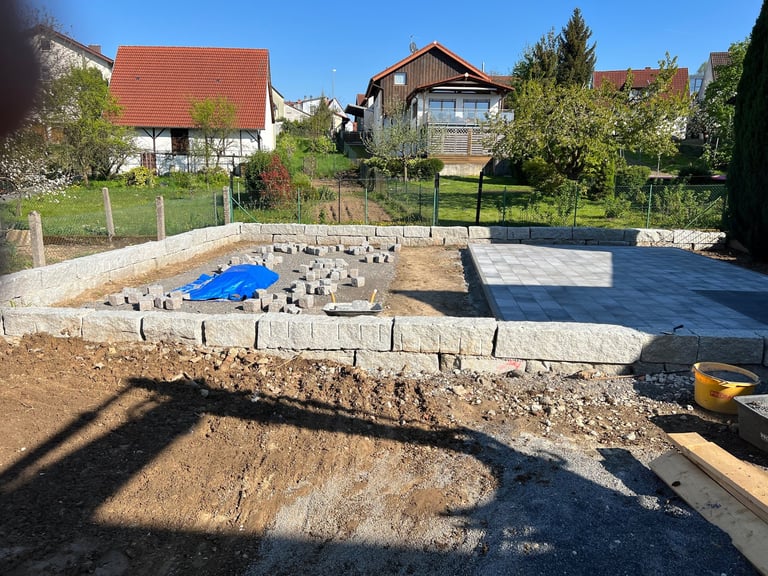 Construction site with foundation and concrete base, residential houses in background on sunny day
